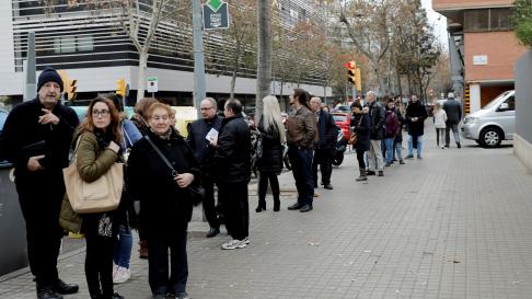 Varias personas hacen fila para votar en un colegio electoral en Barcelona.