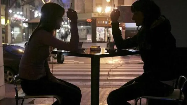 Dos clientes fuman en una cafetería del centro de Zaragoza mientras toman un café
