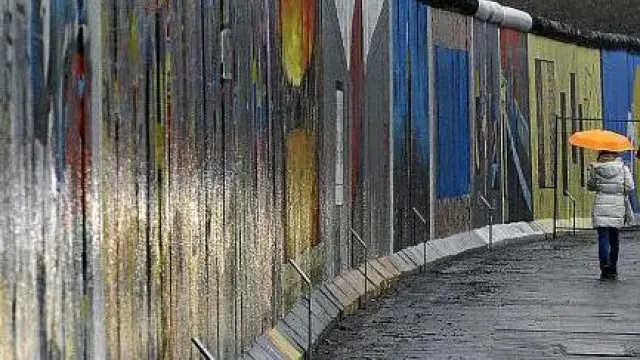 Una mujer pasea junto a un segmento del East Side Gallery de Berlín, el tramo más largo que aún queda en pie del muro.