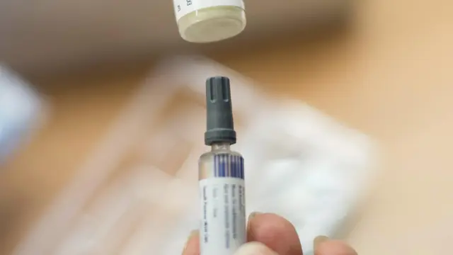 Una enfermera sostiene una vacuna contra el sarampión, la rubeola y las paperas