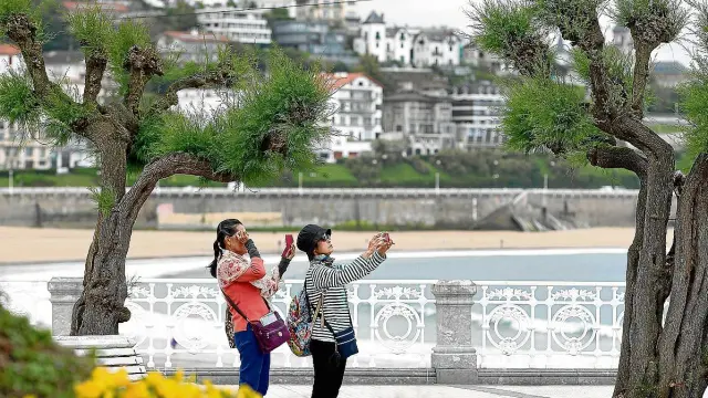 Dos turistas extranjeras toman fotos junto a la playa en San Sebastián.