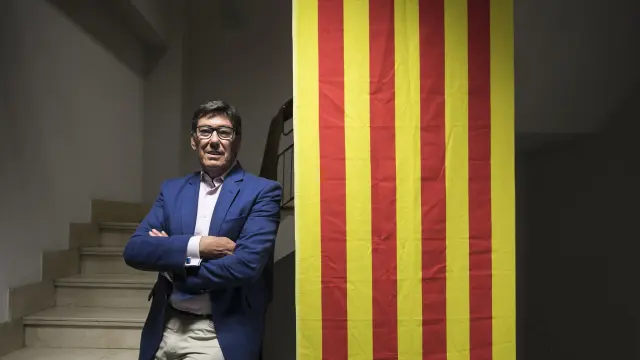El presidente del PAR, Arturo Aliaga, junto a la bandera que preside la sede de su partido, en el Coso de Zaragoza.