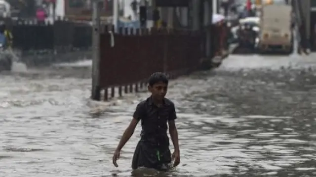 Un joven huye de la corriente de agua provocada por las lluvias.