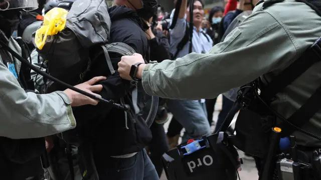 Dos policías retienen a uno de los manifestantes este domingo en las calles de Hong Kong.