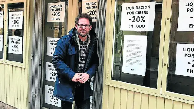 Jorge Álvarez, frente a su tienda en el Coso de Huesca, empapelada de papeles de cierre.