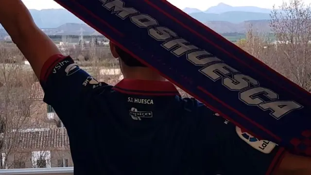 Un aficionado de la SD Huesca se asoma a su ventana para cantar el himno.