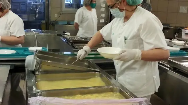 Una de las trabajadoras de la cocina del Servet sirve una ración en un plato.
