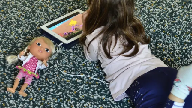 Una niña mirando unos dibujos durante el confinamiento en Valencia.