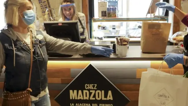 Una voluntaria de la AECC recoge un pedido a domicilio en la tienda de Chez Marzola, de Elena Bernad.