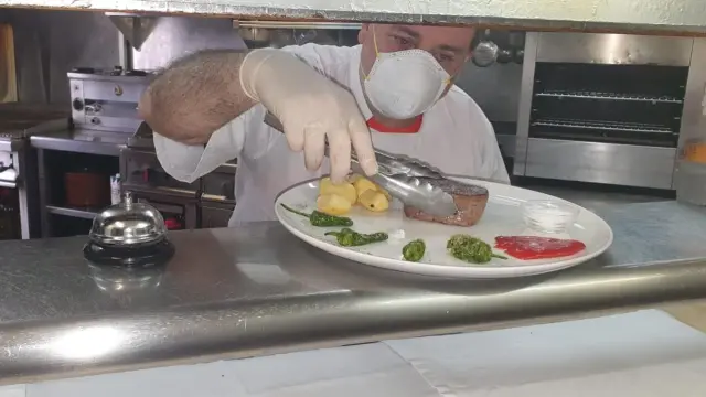 Ángel Lamenca, del hotel Sarao de Escarilla, preparando un plato en su restaurante, que ofrece servicio de terraza y de comida para llevar.