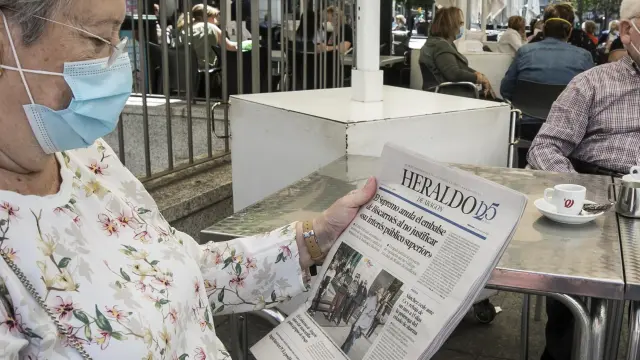 Una pareja lee la prensa mientras toma un café, en una terraza de Zaragoza