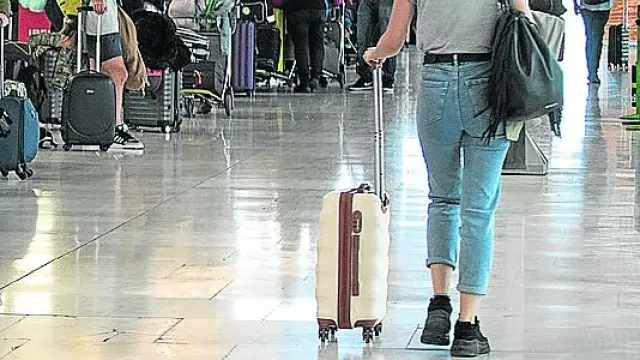 Viajeros esperando para facturar sus maletas en el aeropuerto de Barajas, en Madrid.