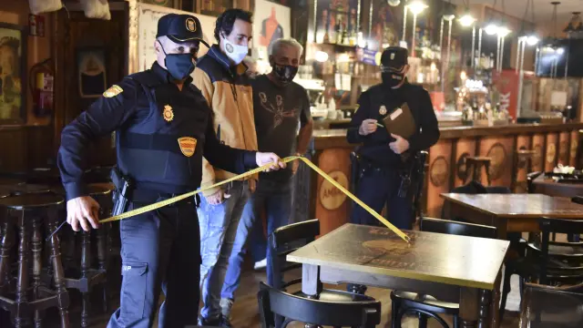 Agentes de la Unidad Adscrita, midiendo la distancia entre mesas de un bar de Huesca.