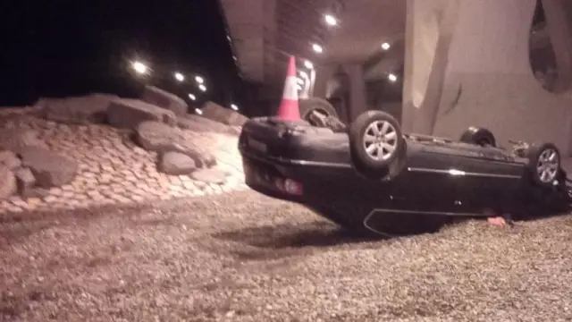 El coche ha quedado volcado en medio de la rotonda.