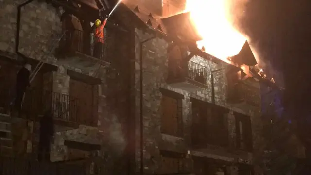 Labores de extinción de los bomberos en el bloque de apartamentos de Sallent de Gállego.