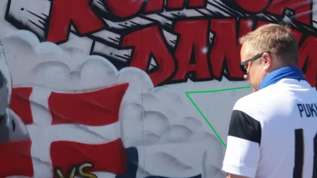 Un aficionado finlandés, delante de un muro con grafitis y mensajes de apoyo a Eriksen en Copenhague