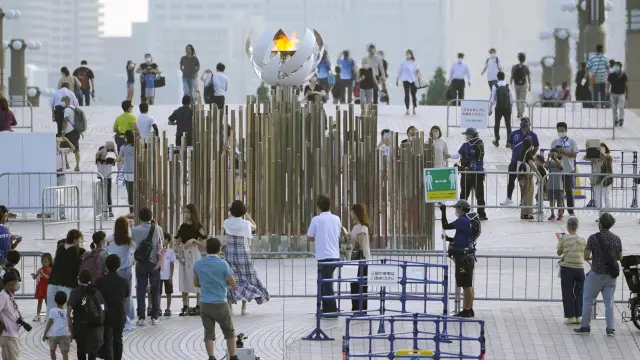 Gente alrededor de la llama olímpica en Tokio.