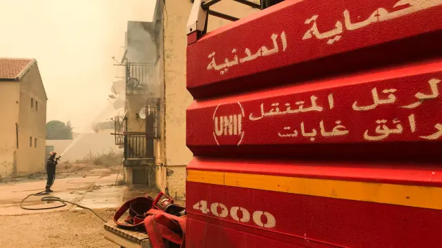 A firefighter attempts to put out a fire at a building in Ain al-Hammam village