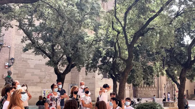 Grupo de turistas frente al Ayuntamiento de Huesca durante una visita guiada a la ciudad.