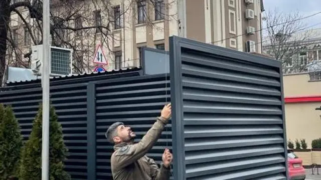 Un geo retira la bandera de la Embajada de españa en Kiew (Ucrania) que ha quedado cerrada esta mañana.