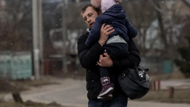 Un hombre con su hija huye de los bombardeos sobre la ciudad ucraniana de Irvin