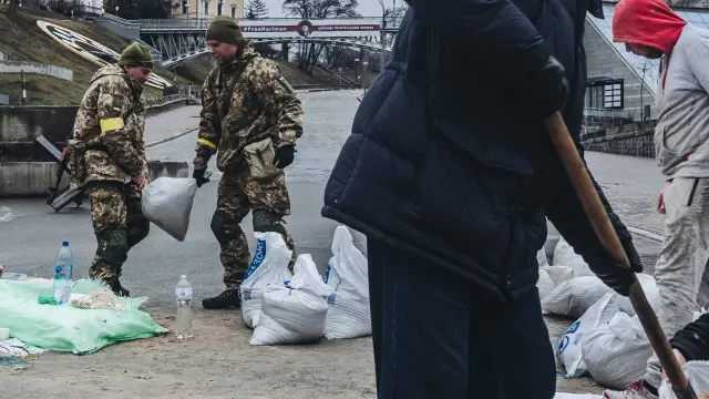 Soldados y voluntarios cargan sacos de arena para construir barricadas en la plaza Maidan de Kiev.