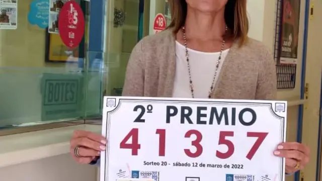 Andrea Ballesté muestra el cartel del nuevo premio repartido entre sus clientes.