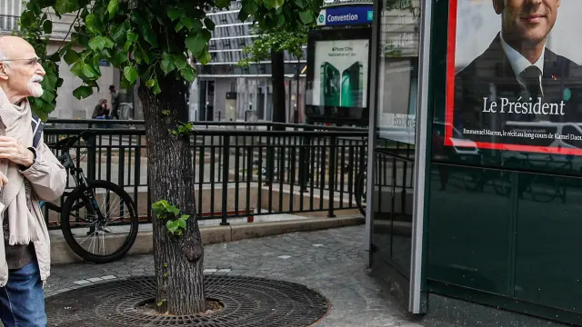 Un hombre camina junto a un kiosco en el que figura una portada del seminario Le Point, que informa de la victoria de Macron, este lunes en París.