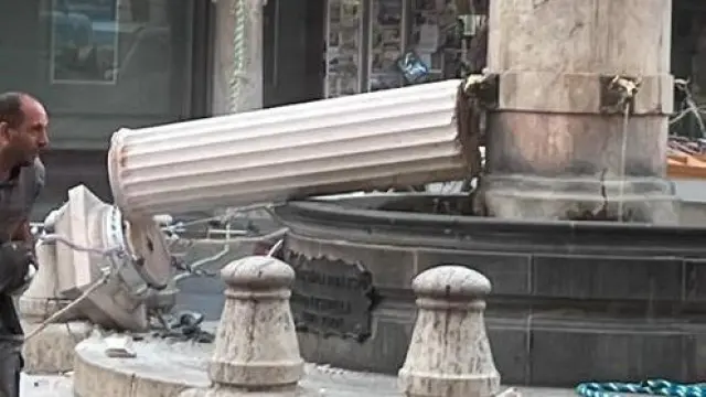 Un operario recoge la figura del Torico del suelo tras haberse desplomado la columna de la fuente.