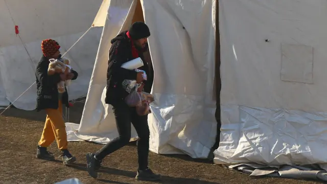 Dos personas llevan artículos donados en un campamento de refugiados afectados por el terremoto en Kahramanmaras, Turquía.