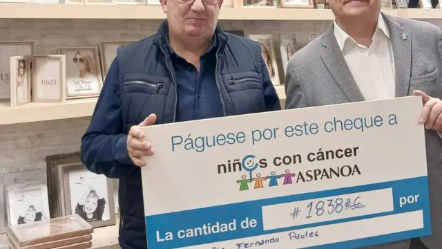 El fotógrafo oscense Fernando Paúles entregando el cheque solidario de su empresa al gerente de Aspanoa, Juan Carlos Acín,