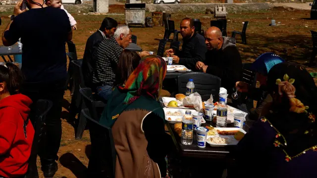 Refugiados turcos comen al aire libre en la devastada ciudad de Nurdagi.
