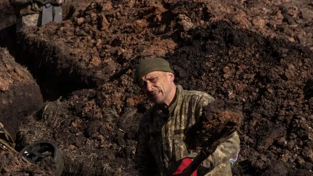 Un soldado ucraniano cava una trinchera en el frente de Bajmut mientras otro compañero vigila.