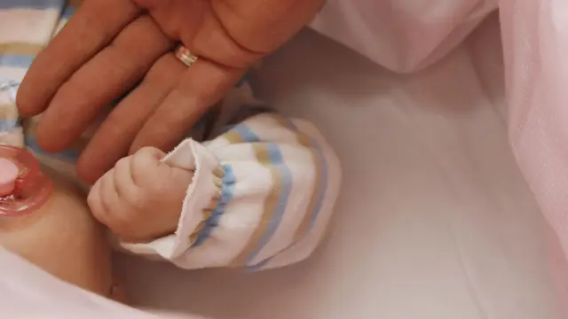 Un bebé, nacido con técnicas de fertilización artificial, sujeta el dedo de su madre.