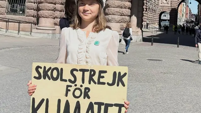 Greta Thunberg con un cartel que dice "Huelga escolar por el clima".