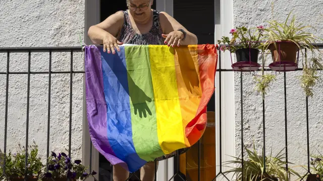 Una mujer coloca una bandera Lgtbi en un balcón.