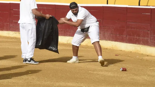 Personal de la plaza de toros de Huesca limpiando el ruedo de latas.