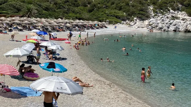 Varias personas toman el sol en una playa de la isla griega de Skópelos, en las Espóradas.