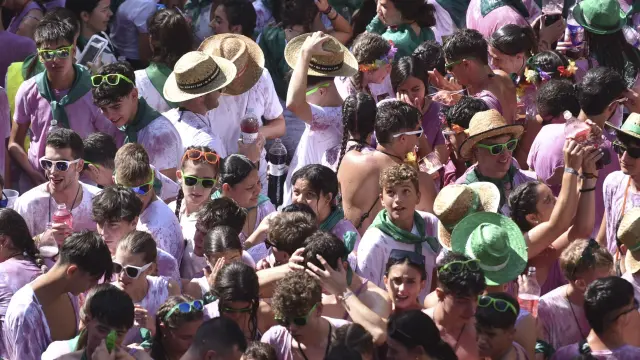 El chupinazo de Huesca es una marea morada de jóvenes con las camisetas blancas teñidas por el vino.