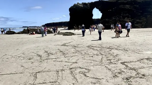 Los nombres de dos pueblos aragoneses escritos en la arena de la playa de las Catedrales, en Lugo.