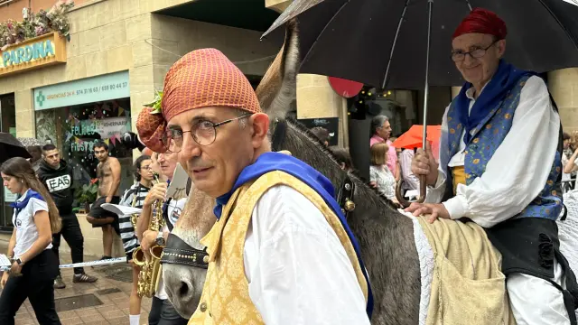 El Pregonero del Vero, Felipe Sallán, a lomos de un burro y protegido con su paraguas, participa en la Cabalgata del Pregón de las fiestas de Barbastro