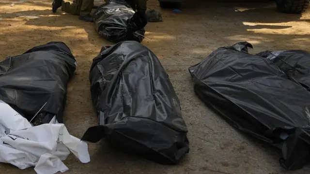 Soldados israelíes junto a los cuerpos de israelíes asesinados por militantes de Hamas en el kibutz Kfar Azza.