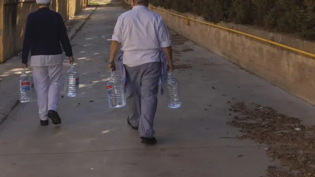 El equipo de cocina del colegio Moncayo de Tarazona vuelve al centro tras rellenar las garrafas de agua en el depósito que la DGA ha instalado en el patio del centro.