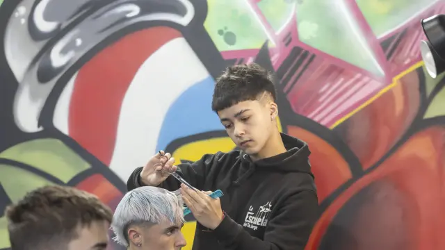 Uno de los alumnos corta el pelo a un cliente en la Escuela del Tío Jorge, este lunes en Zaragoza.