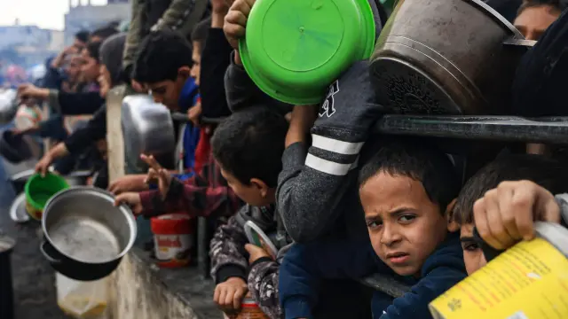 Niños palestinos en la Franja de Gaza esperan a recibir alimentos, en una imagen de archivo.