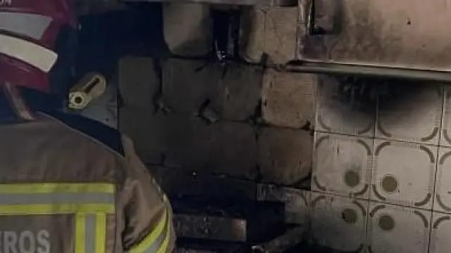 Un bombero realizando tareas de extinción de un incendio en la cocina de una vivienda de Huesca.