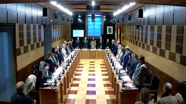 Imagen del último minuto de silencio por las víctimas de violencia machista en el último pleno del Ayuntamiento de Huesca con los dos concejales de Vox (a la derecha) sentados.