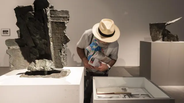 La escultura, a la izquierda, se expone junto a una vitrina con fotografías y un cuaderno personal del artista.