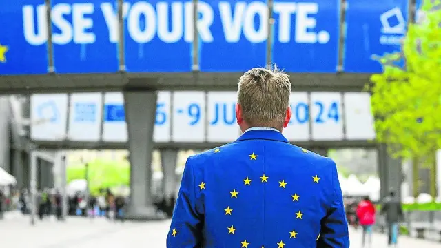 Un hombre vistiendo una chaqueta europea frente a la sede del Parlamento Europeo.