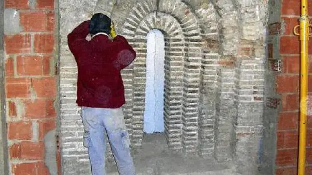 Un obrero trabaja en la rehabilitación del arco aparecido en la que será la casa del párroco